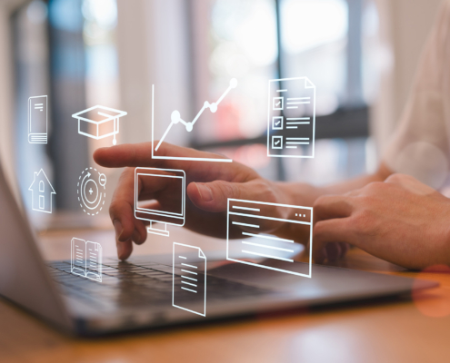 Side view of a man typing on computer with digital graphics floating in air